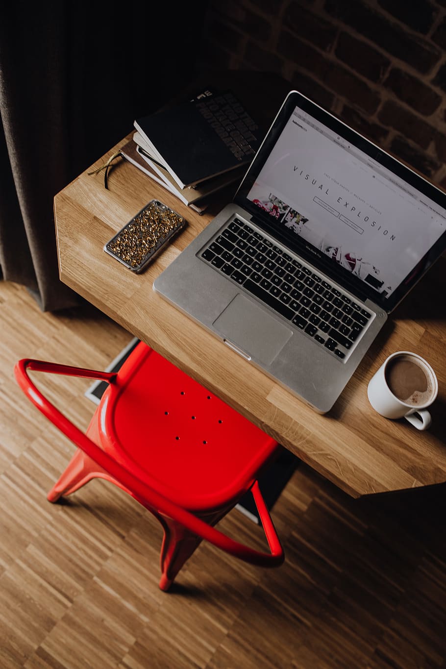 Creatives desk with laptop, camera, journals and books in front of brick wall HD wallpaper