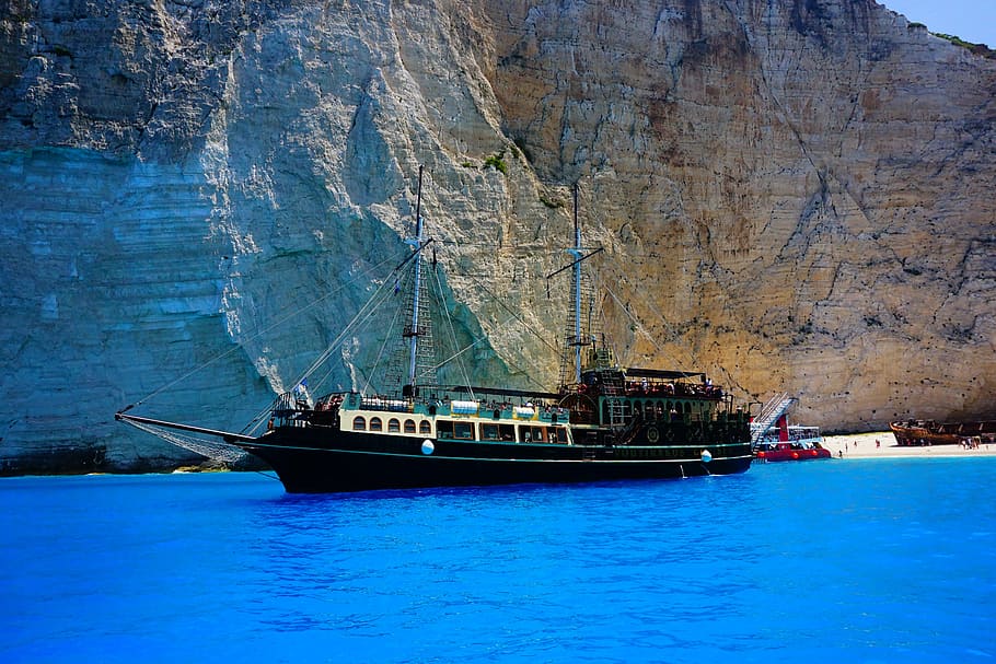 Black Ship at Sea Near Rock Formation, bay, beach, blue, blue waters HD wallpaper