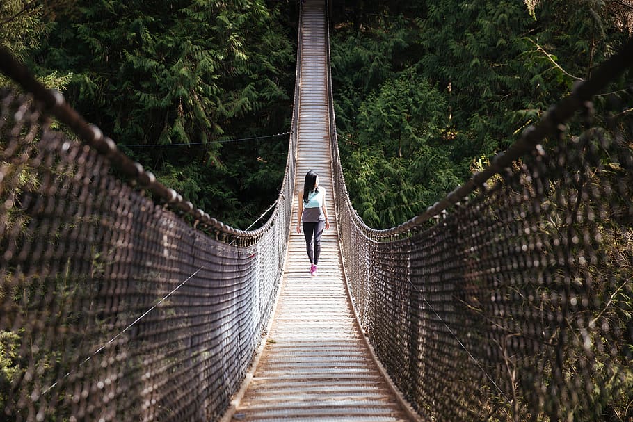 Woman Wearing Blue Sleeveless Shirt Walking on Bridge at Daytime HD wallpaper