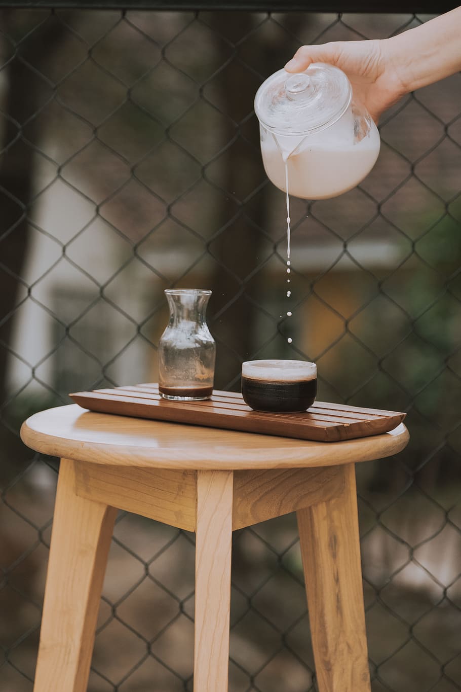 person holding clear glass pitcher pouring round black cup, milk HD wallpaper