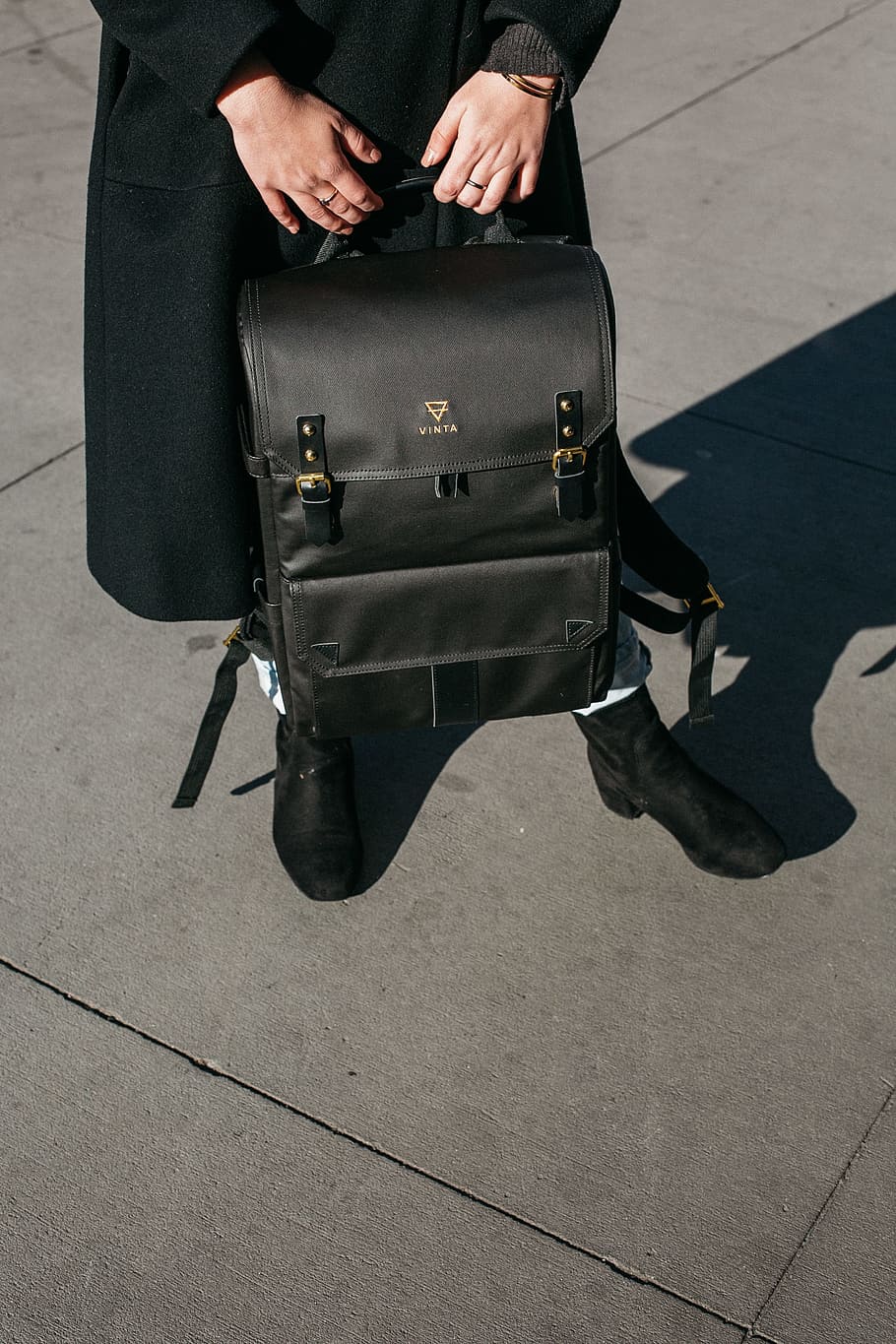 Person Wearing Black Coat Holing Black Leather Knapsack Backpack Standing on Concrete Ground HD wallpaper