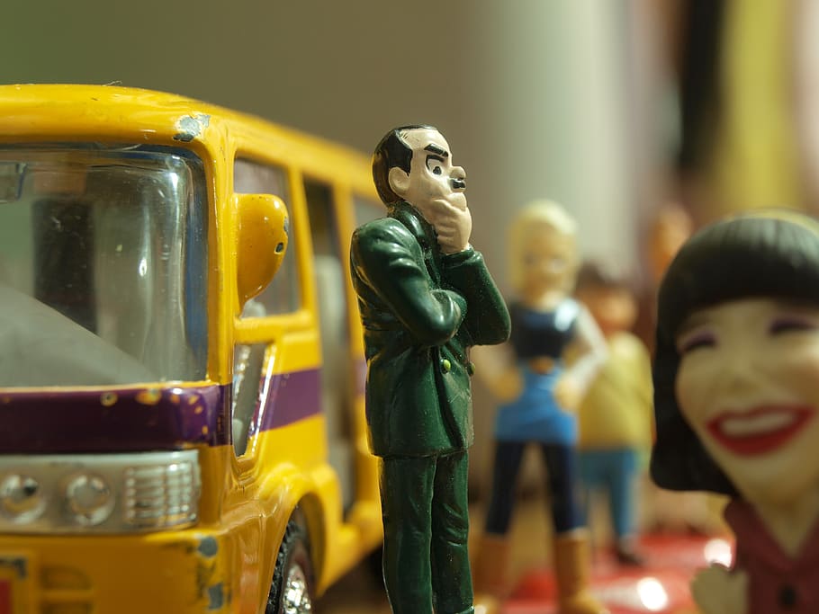 Man in Green Coat Figure Standing in Front of Yellow Toy Bus HD wallpaper