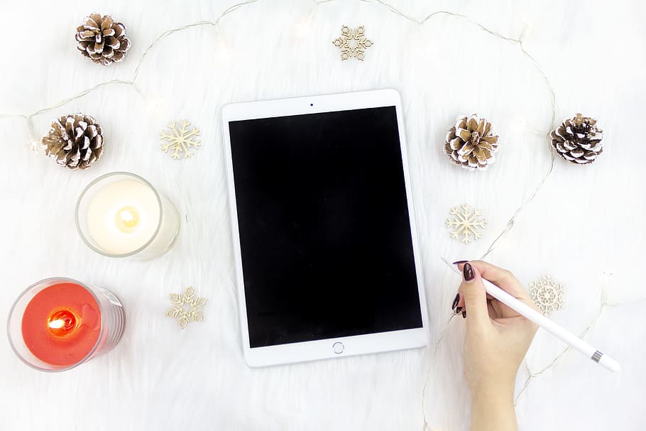 person holding Apple Pencil beside of iPad, candle, snowflake HD wallpaper