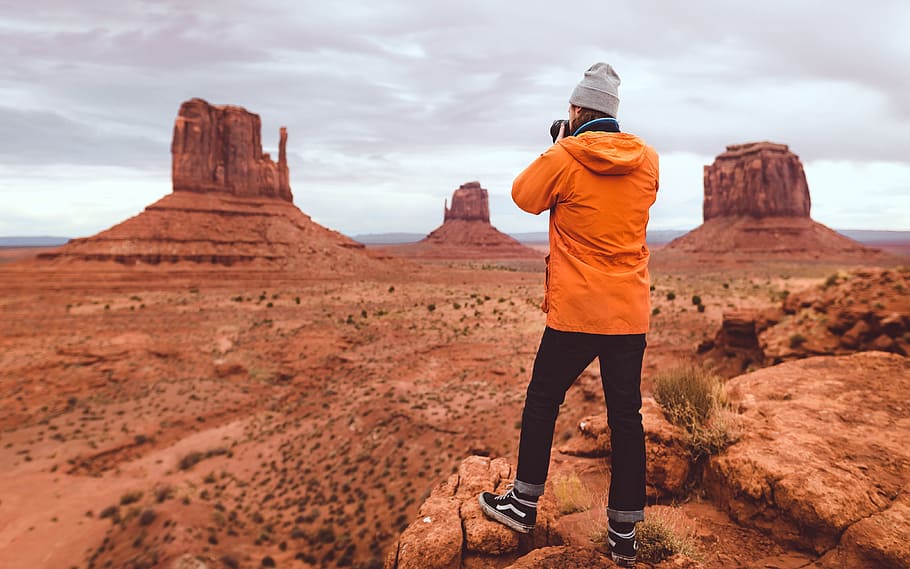 man standing on rock formation, orange, jacket, arizona, desert