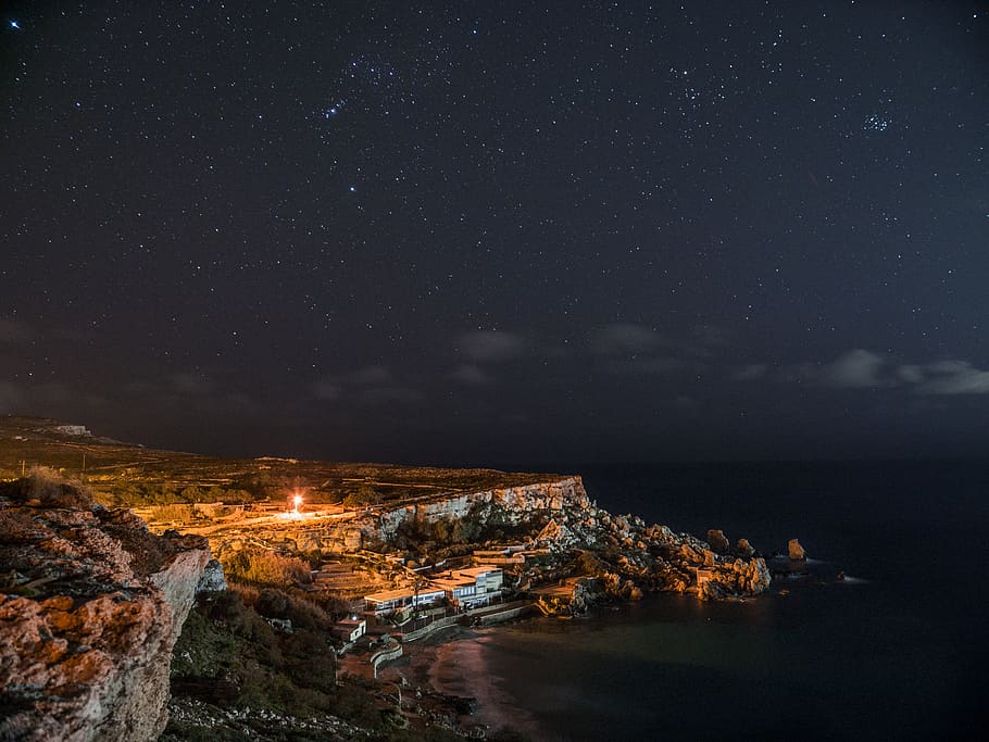 Rock Cliff Near Body of Water Under Clouds and Sky during Nighttime HD wallpaper