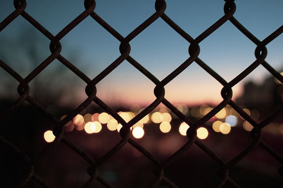 Selective Focus Photography of Silhouette Fence Near Bokeh Light