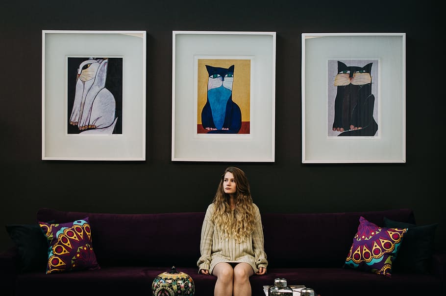 woman sitting on brown sofa above three cat paintings, print, HD wallpaper