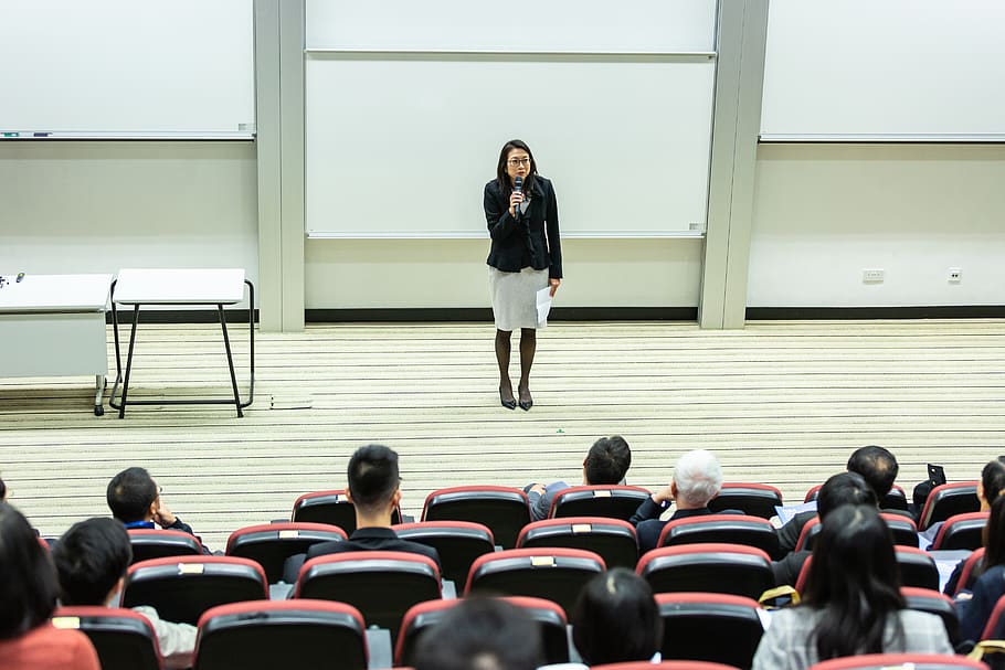 Woman Holding Microphone Standing in Front of Crowd, chairs, class HD wallpaper