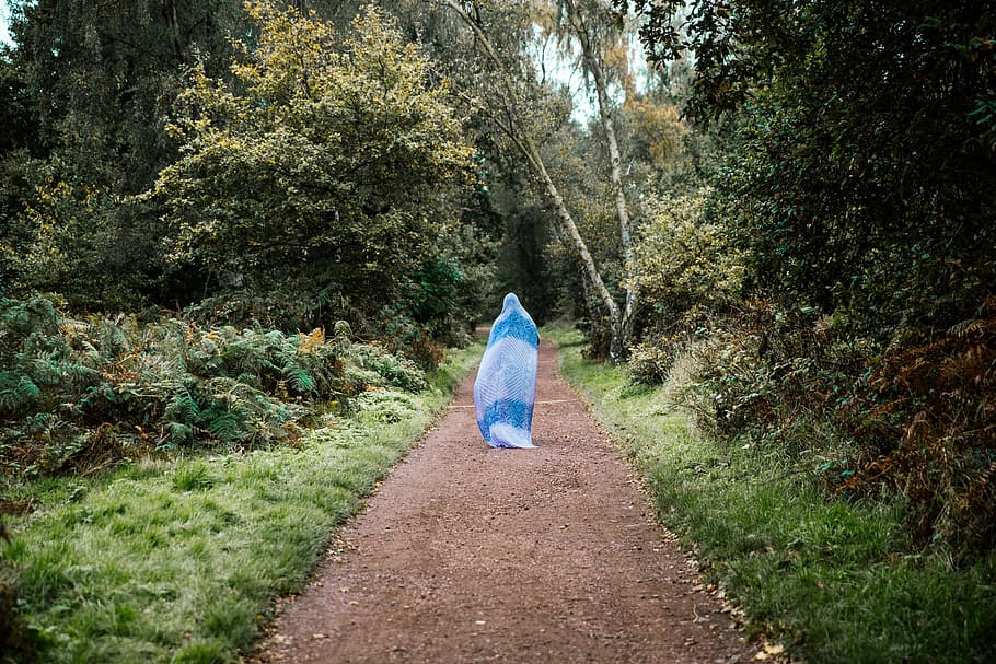 A woman walking on a forest path with her entire body covered HD wallpaper