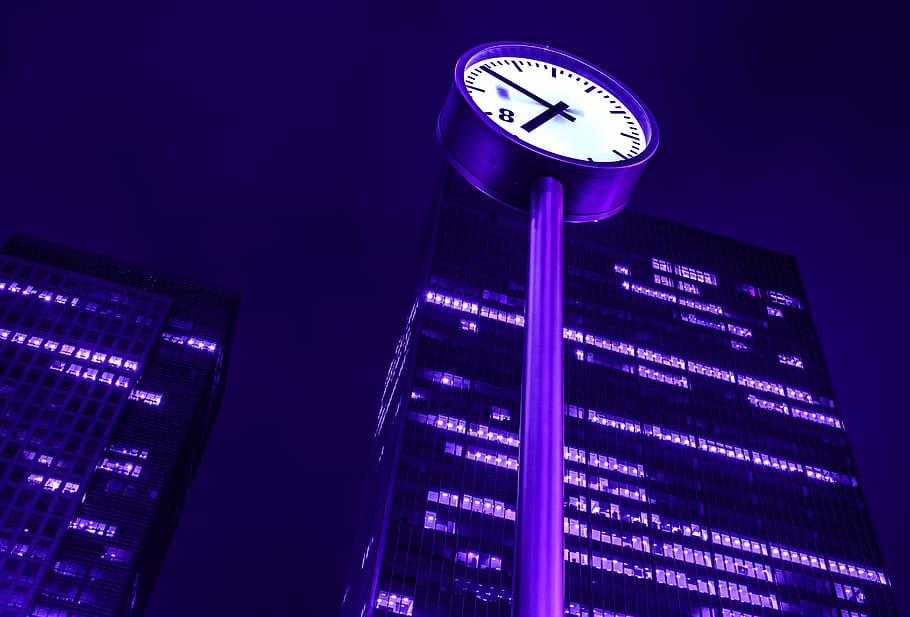 low-angle photography of clock post near curtain wall high-rise building during night, HD wallpaper