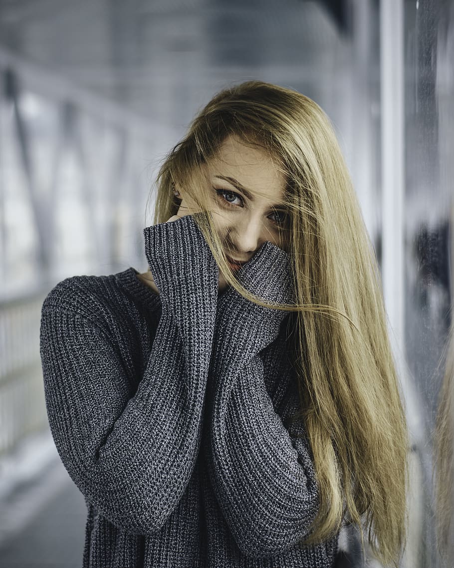 woman in gray knitted sweater with hands on cheeks, one person