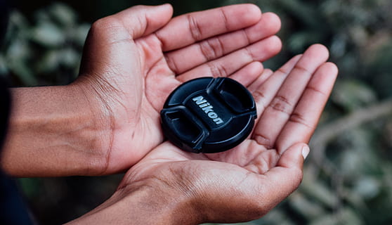 Black Nikon Camera Lens Cover on Left and Right Human Palms, blurred background HD wallpaper