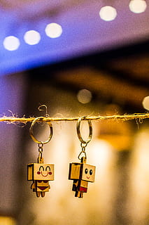 Bokeh Photography of Two Wood Block Man and Woman Figure Key Chains Hanging on Brown Thread HD wallpaper