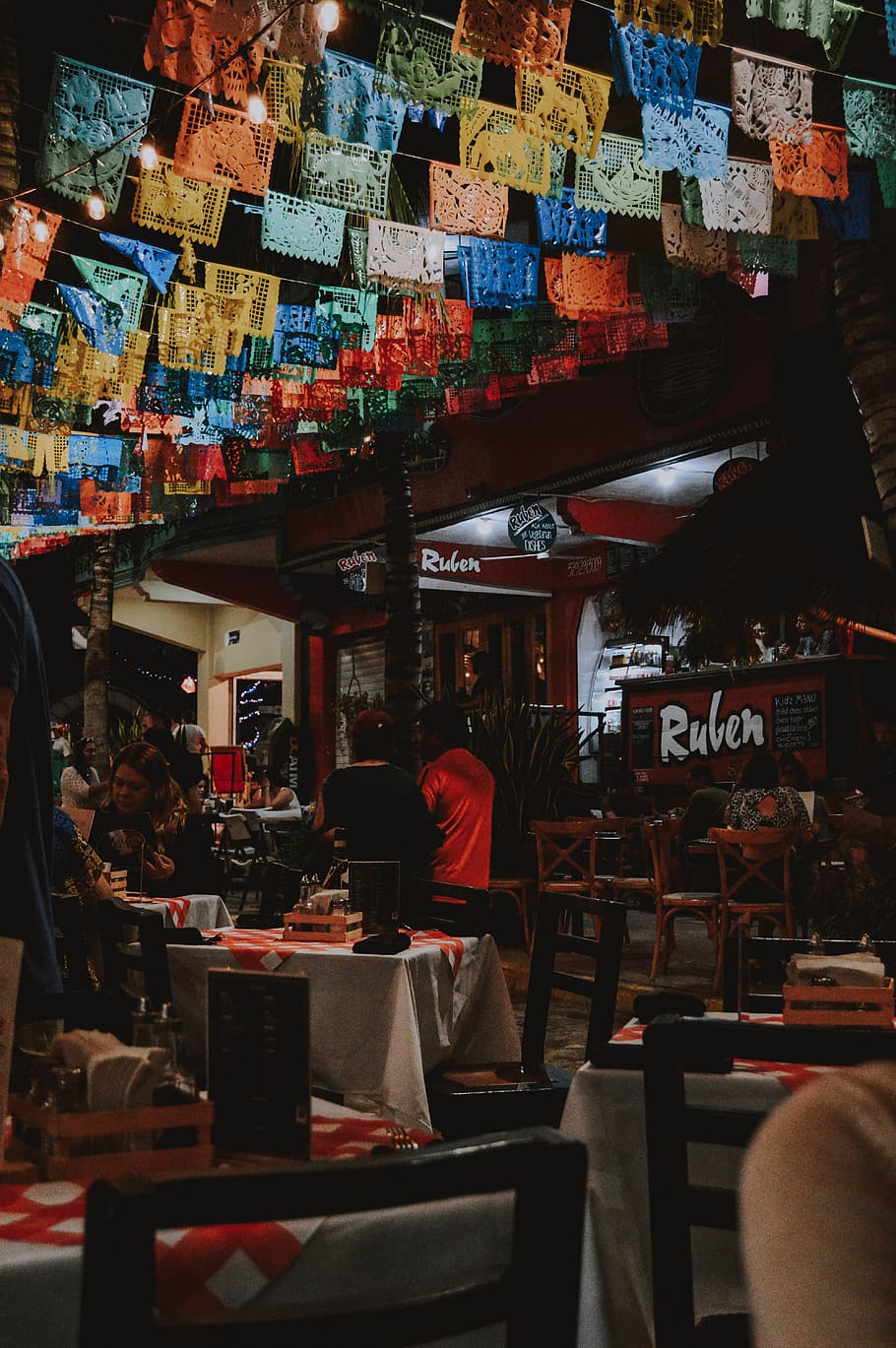 Man and Woman Sitting on Chairs Under the Buntings, bar, building