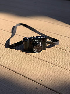black SLR camera with strap on brown surface, electronics, wood HD wallpaper