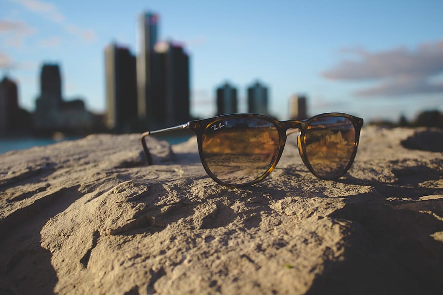 black Ray-Ban framed sunglasses, land, sunlight, sky, beach, focus on foreground