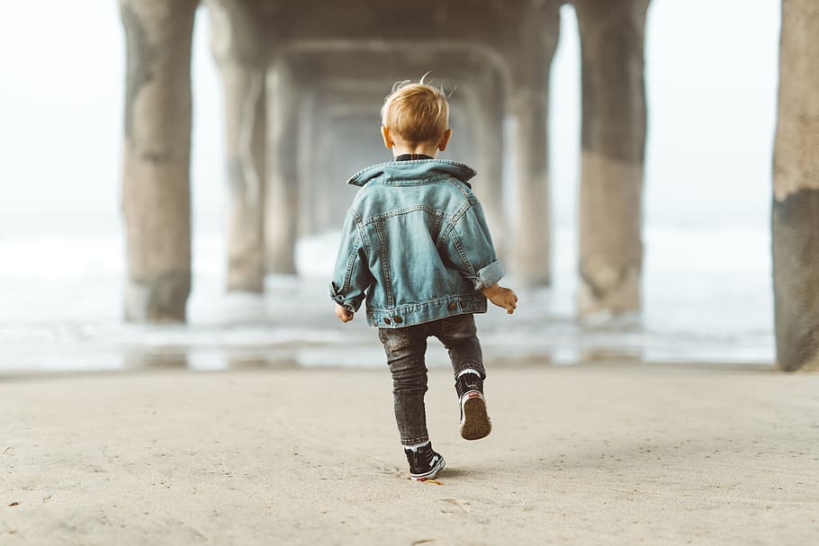 walking boy wearing blue denim jacket under the bridge, child