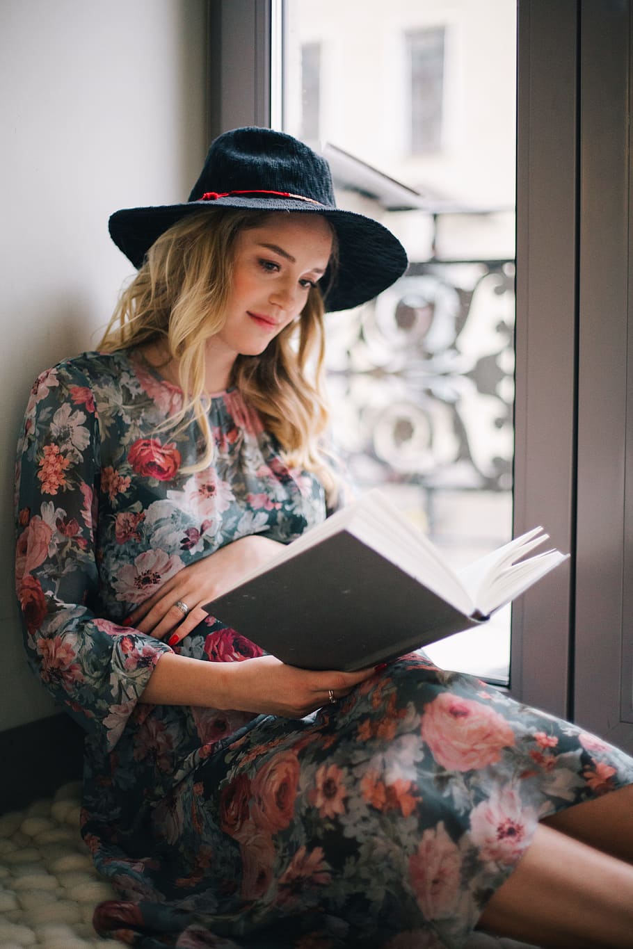 Pregnant Woman Wearing Green, Red, and White Floral Dress Reading a Book Near Window HD wallpaper