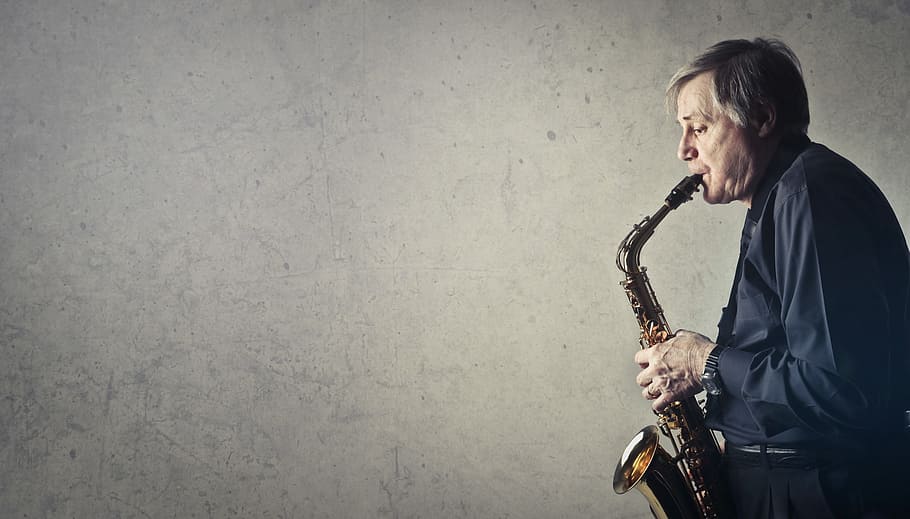 Middle Aged Man Playing Saxophone on Gray Background Wall, 50-60 years