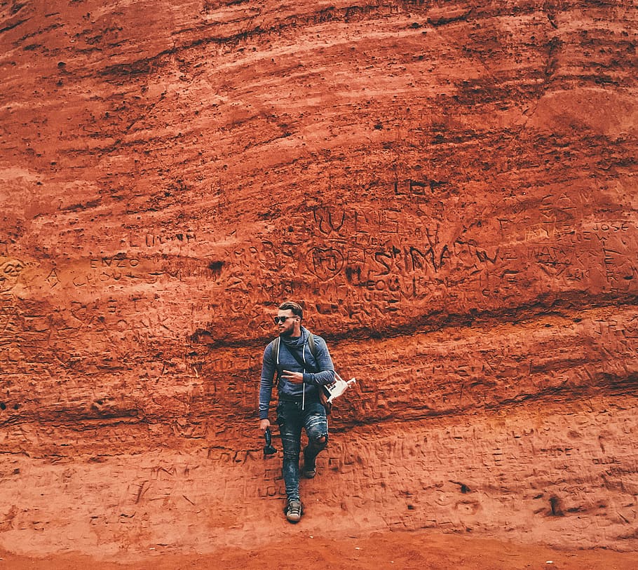 Person Leaning on Brown Wall, arid, barren, canyon, cliffs, daylight HD wallpaper