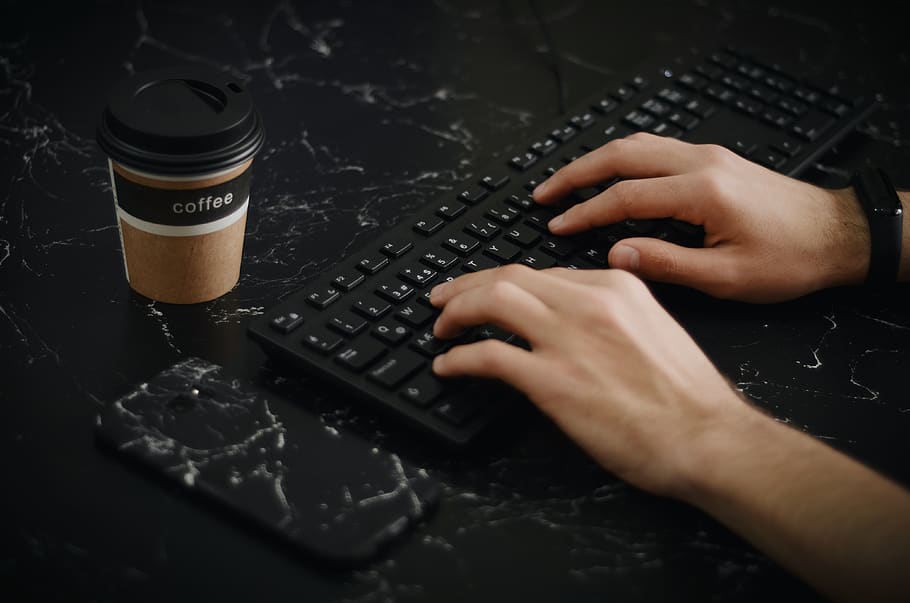 Person Using Keyboard Beside Phone and Coffee Cup, black, close-up