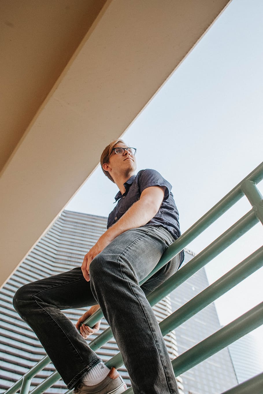 man sitting on gray rail, portrait, glasses, balcony, building HD wallpaper