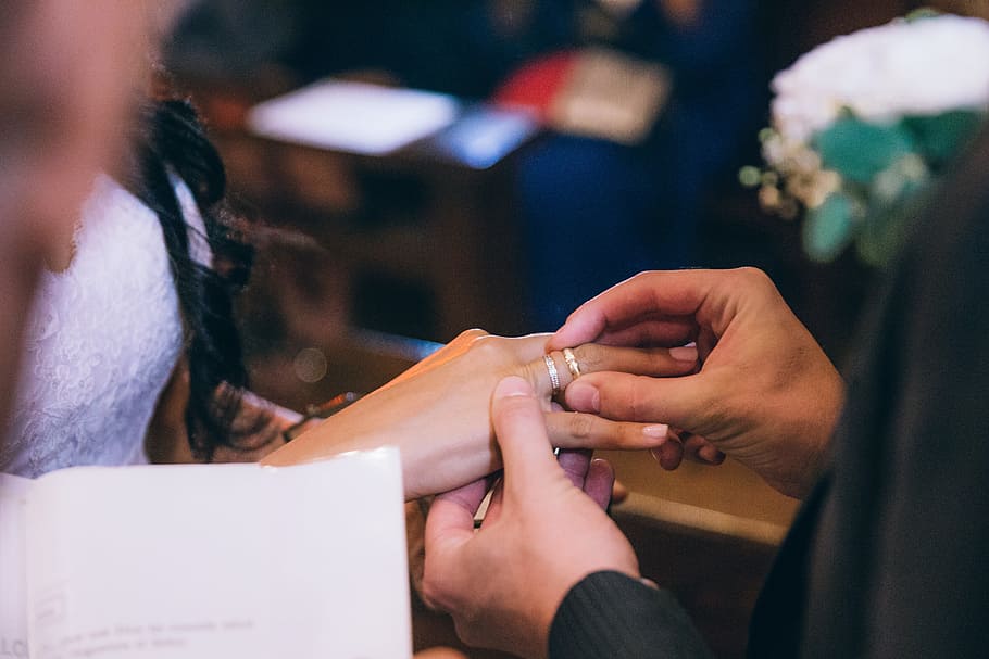 Groom putting wedding ring on the bride s finger in church, black