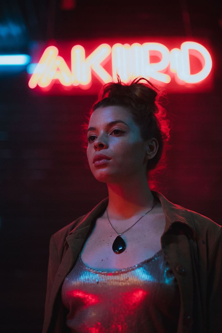 shallow focus photography of woman standing in front of neon sign