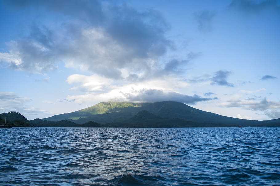 Ocean Near High Rise Mountain Cover With Fogs at Daytime, blue waters HD wallpaper