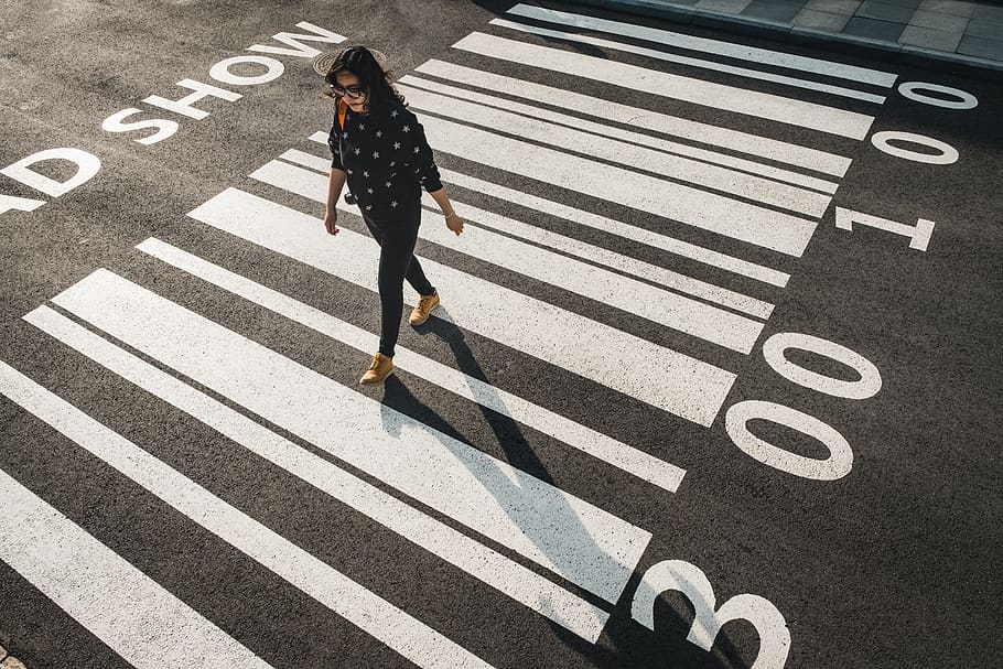 woman walking on pedestrian lane, sign, road marking, one person