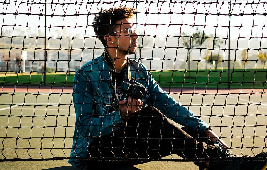 Photo of Man Sitting On Tennis Court, blur, boy, camera, denim jacket HD wallpaper