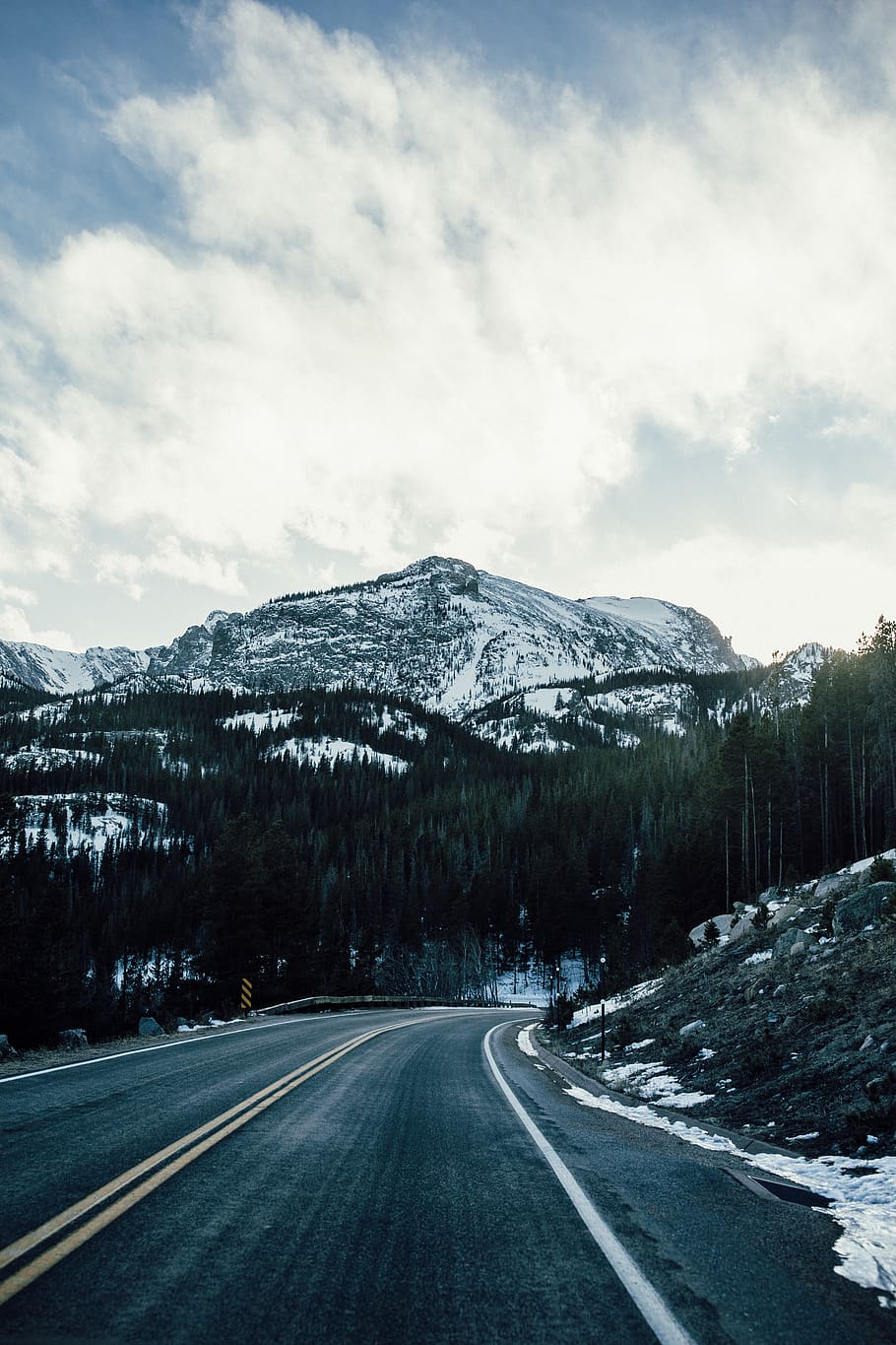 asphalt road between trees overlooking mountain range during daytime HD wallpaper
