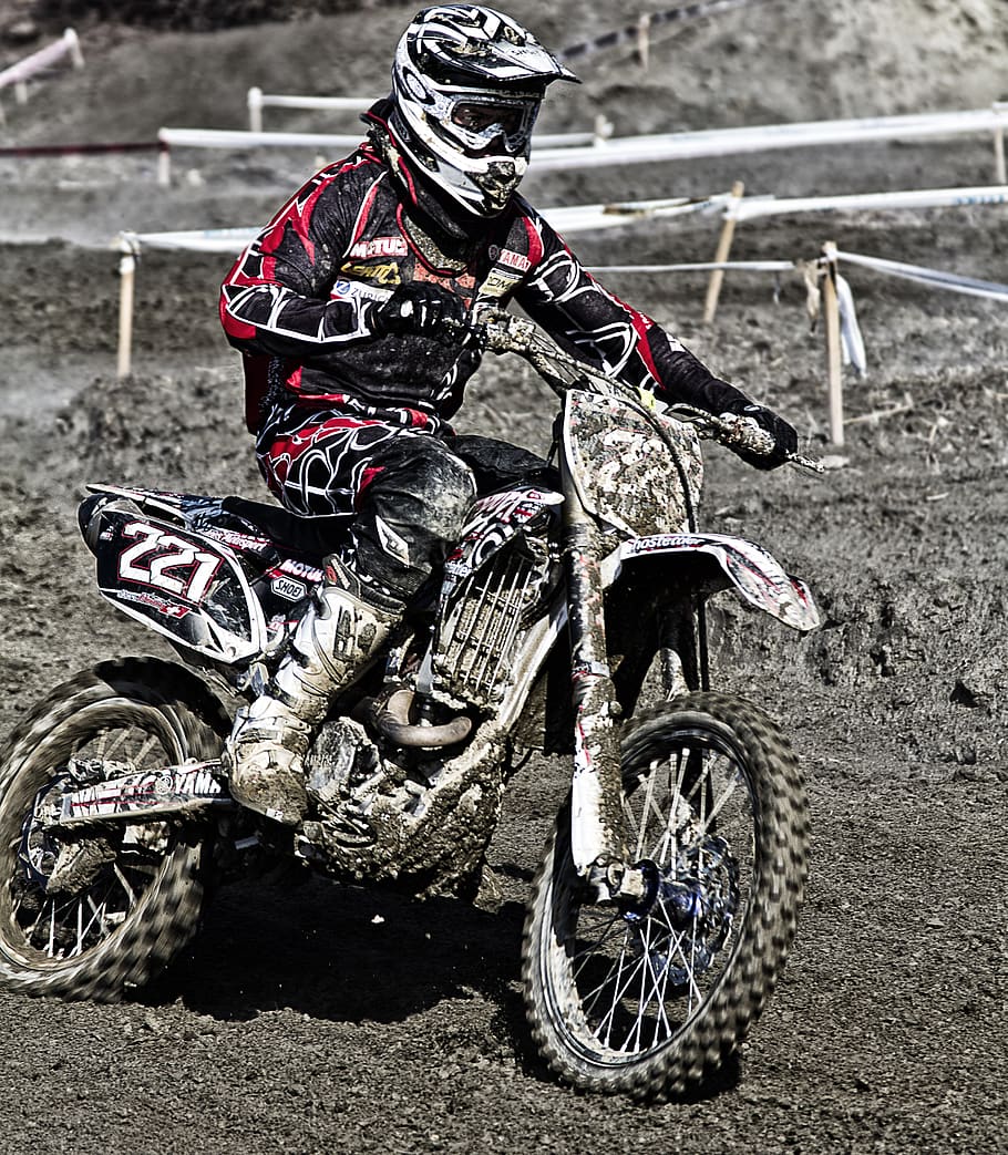 Person Riding on Motorcycle on Motocross Race Track Wearing White and Black Oakley Full Face Helmet during Daytime