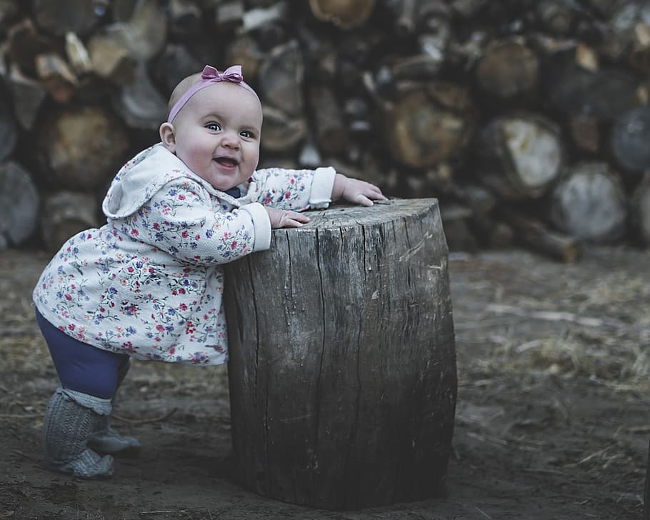 Toddler in White and Pink Jacket Standing Beside Wood Log, baby