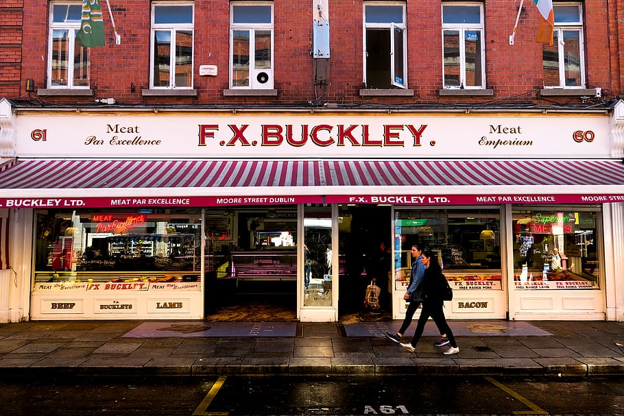 man and woman walking in front of F.X. Buckley store, shop, ireland