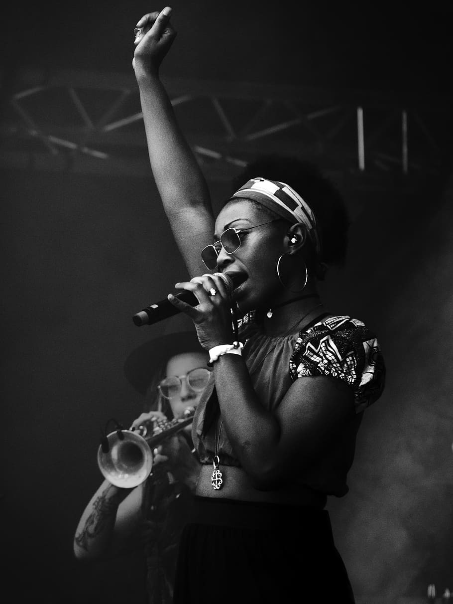 grayscale photography of woman holding microphone, singer, striking pose