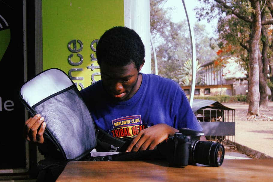 Man Holding Black Dslr Camera, african, bag, blue shirt, camera equipment HD wallpaper