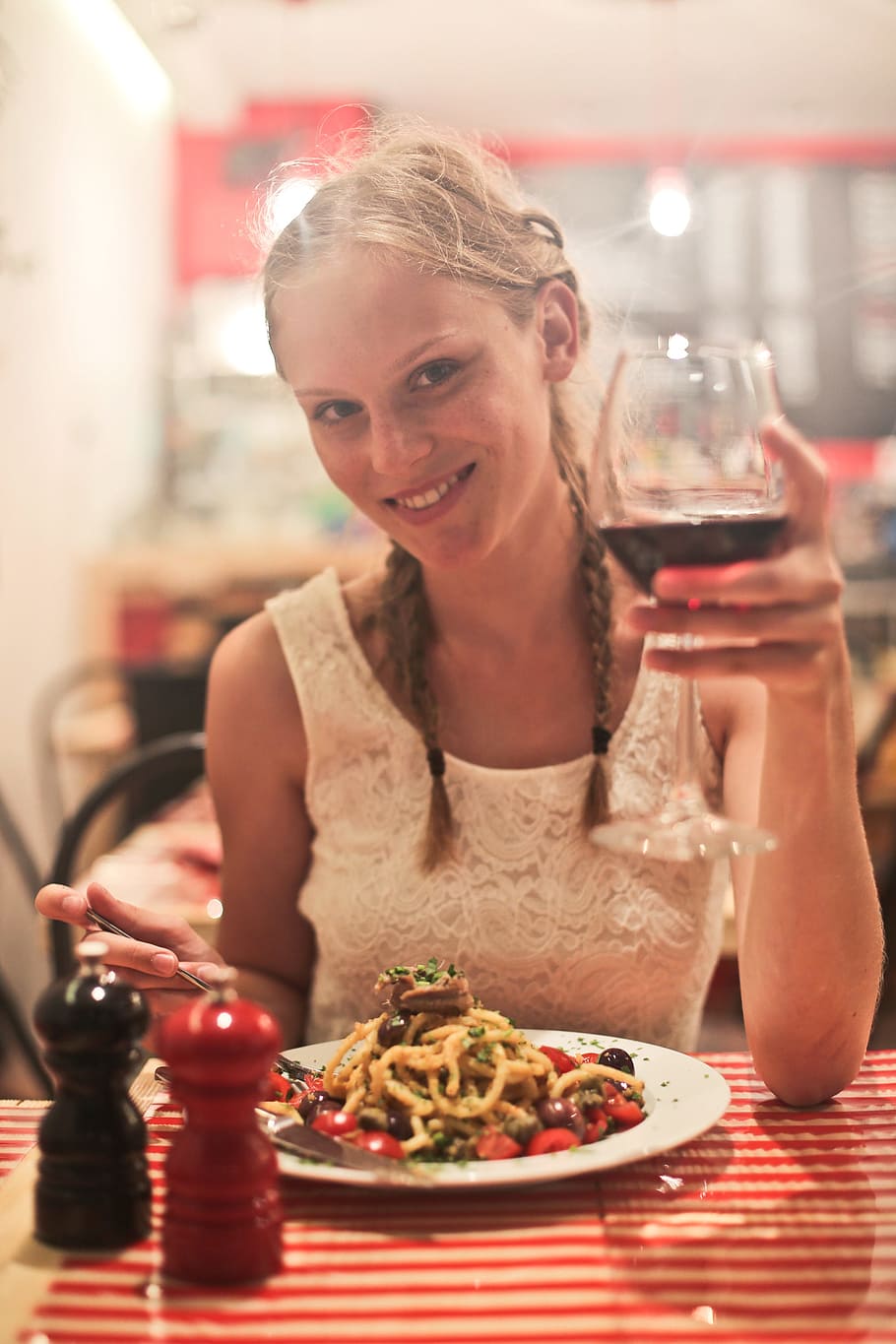Two young blonde women drinking red wine in a restaurant with pasta on the table