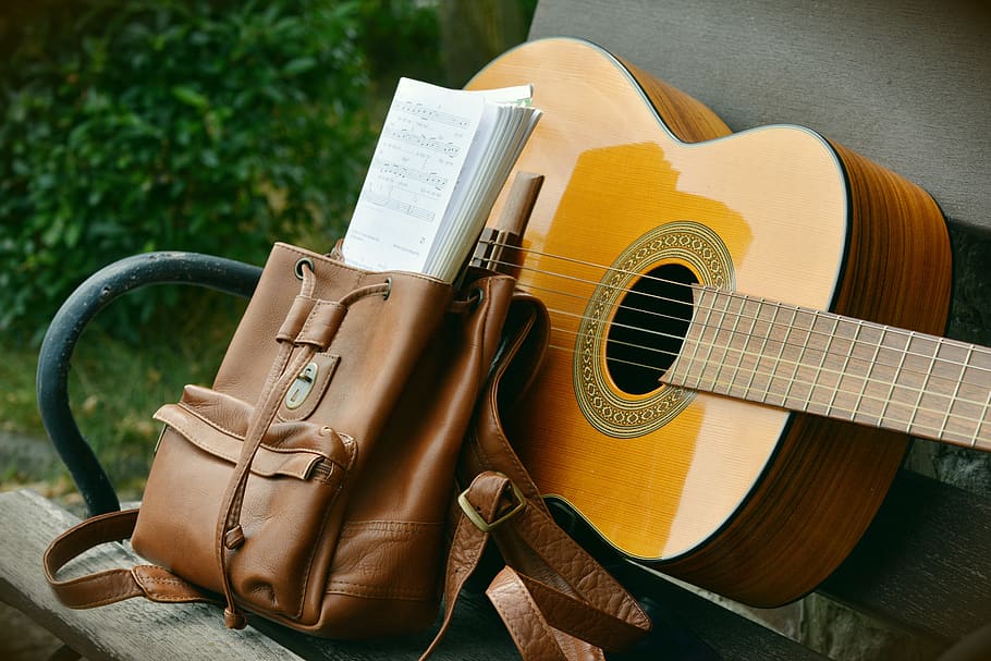 Brown Acoustic Guitar Beside Brown Leather Bucket Backpack on Brown Wooden Bench HD wallpaper