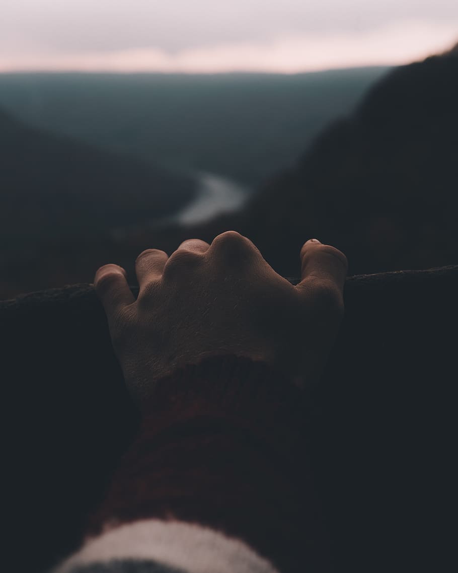 person's hand holding railings overlooking winding river, finger