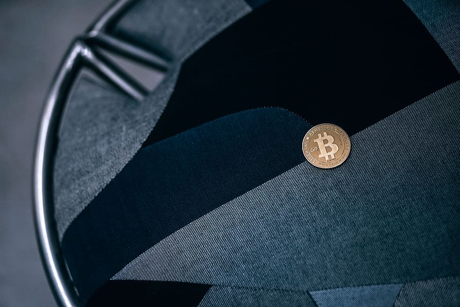 Shining Gold-Plated Physical Bitcoin on a Black and Grey Texture of a Chair. HD wallpaper