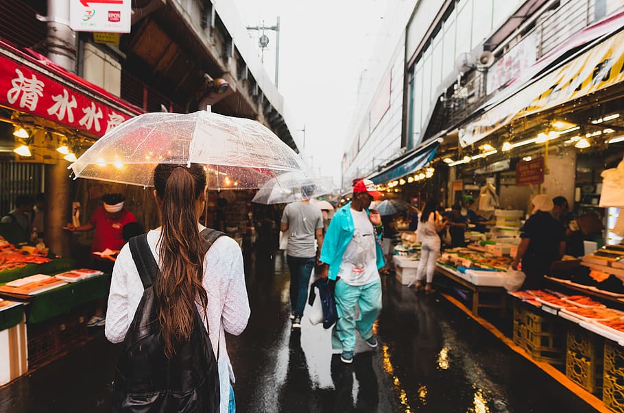 people walking with umbrella on alley between store stalls, human