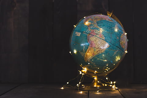 An antique globe with a string of lights wrapped around it on a wooden surface HD wallpaper