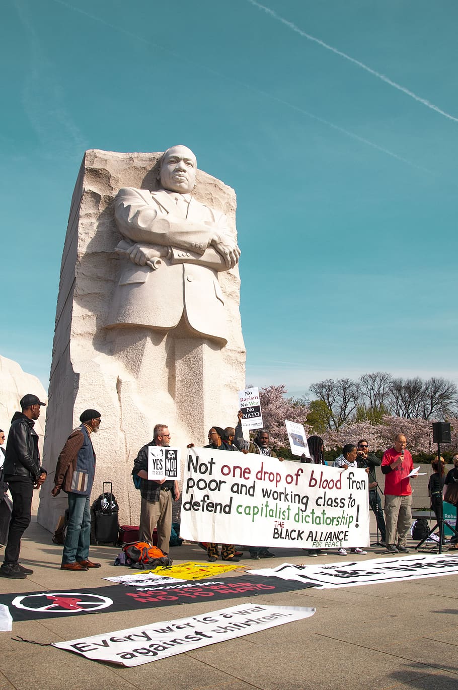 people standing beside statue, person, human, banner, text, crowd
