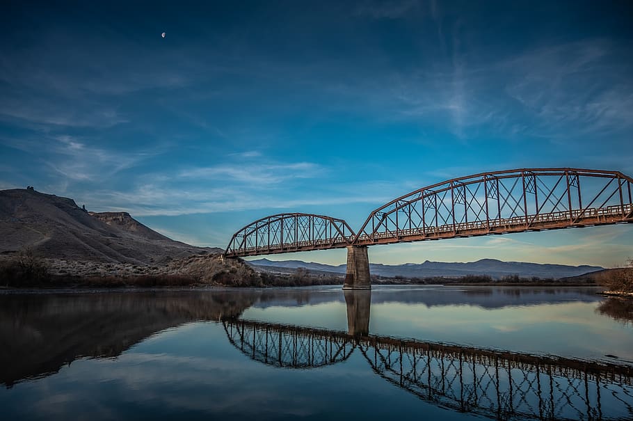 Brown Metal Bridge Reflecting on Clear River Water Beneath Blue Sky HD wallpaper