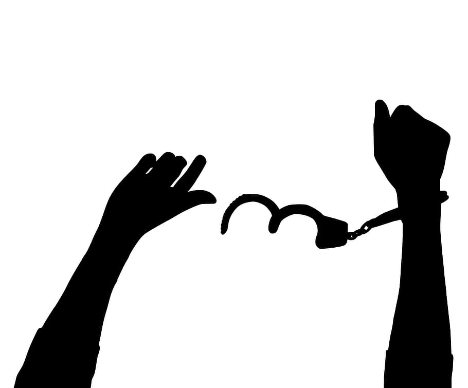 Silhouette of hand freed from handcuffs. One hand out, one hand cuffed.