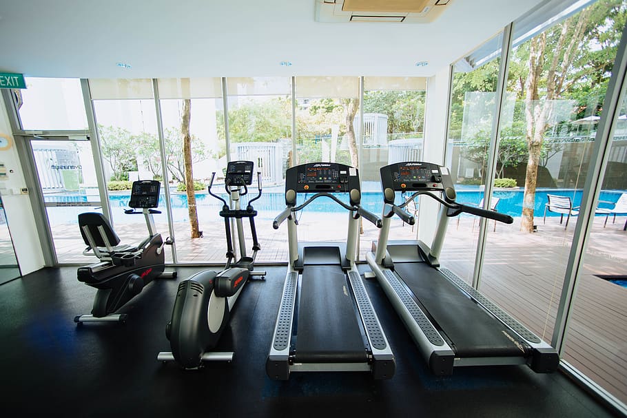black treadmills and elliptical trainers in glass room, indoors