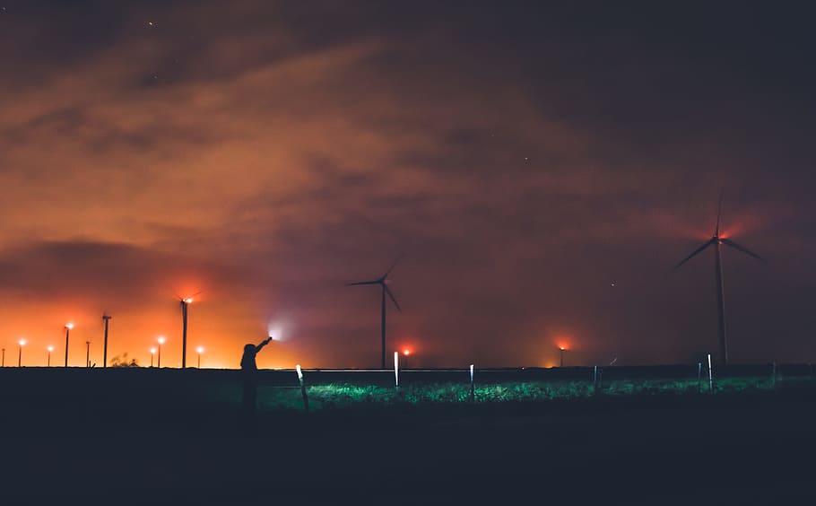 Photography of Person Holding Flashlight Near Windmills during Night Time