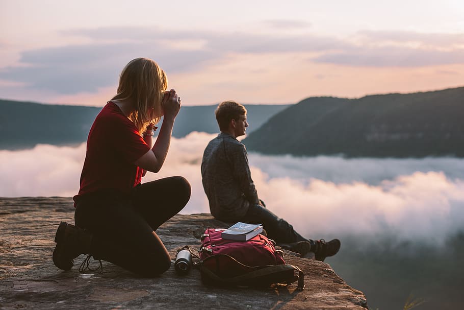 woman taking photo of man sitting on cliff at daytime, person HD wallpaper