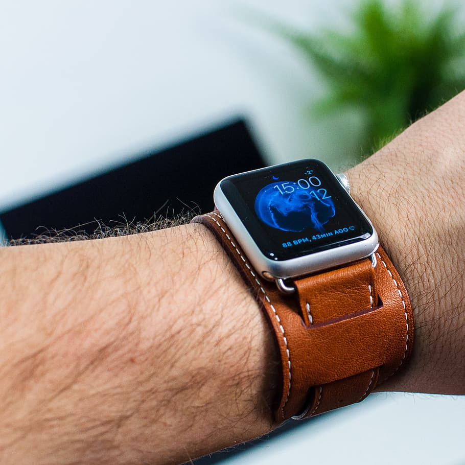 person wearing silver aluminum case Apple Watch with brown leather band